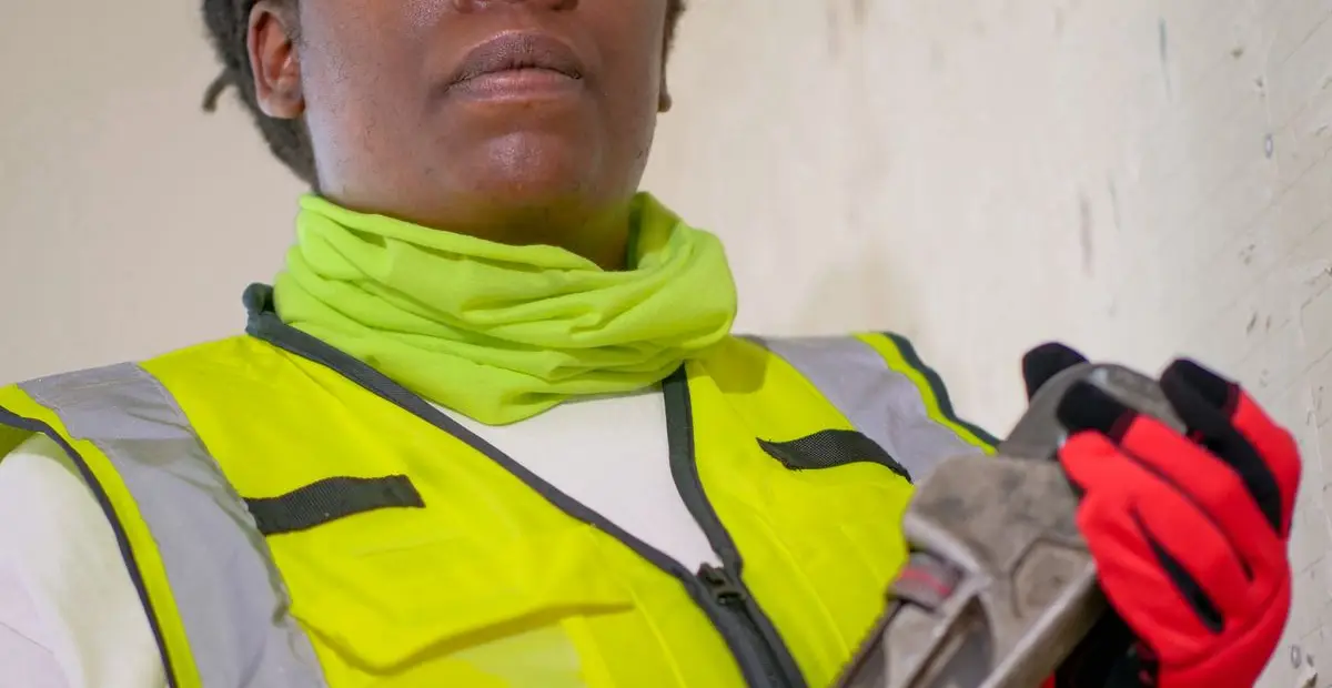 A drain professional in protective gear holding a wrench
