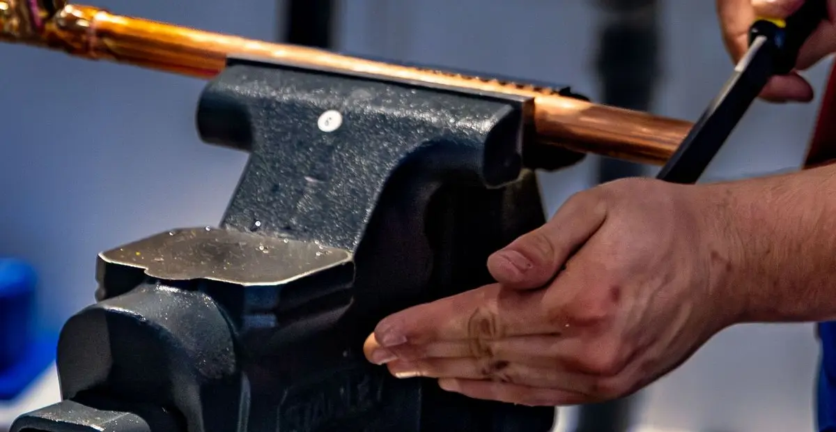 A copper pipe held in a bench vice