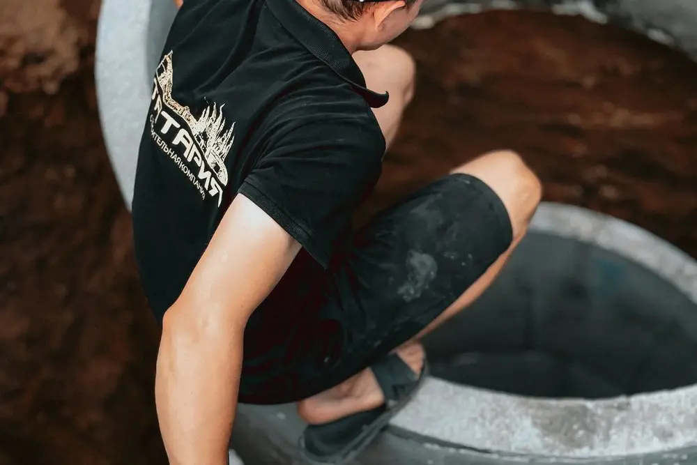 A worker at an open sewer access chamber