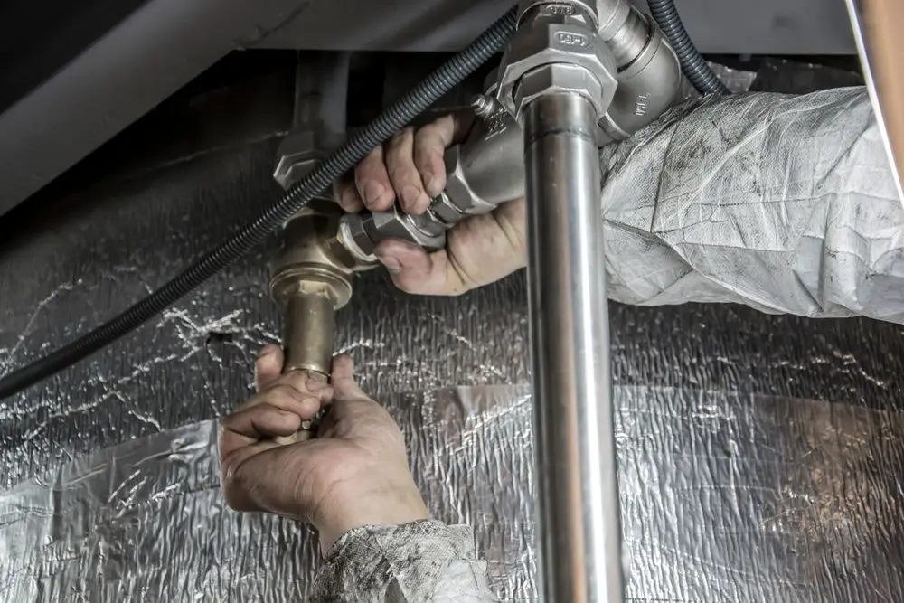 Hands working on the pipes under a sink