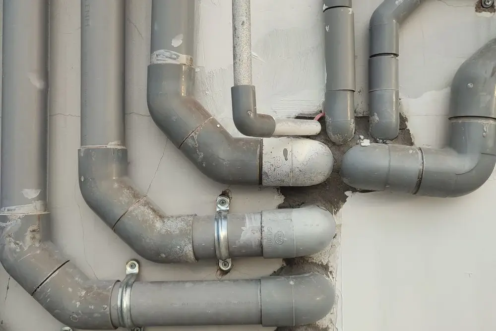 A run of grey main line pipes on a wall